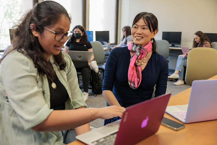 two individuals looking at a laptop in a computer lab